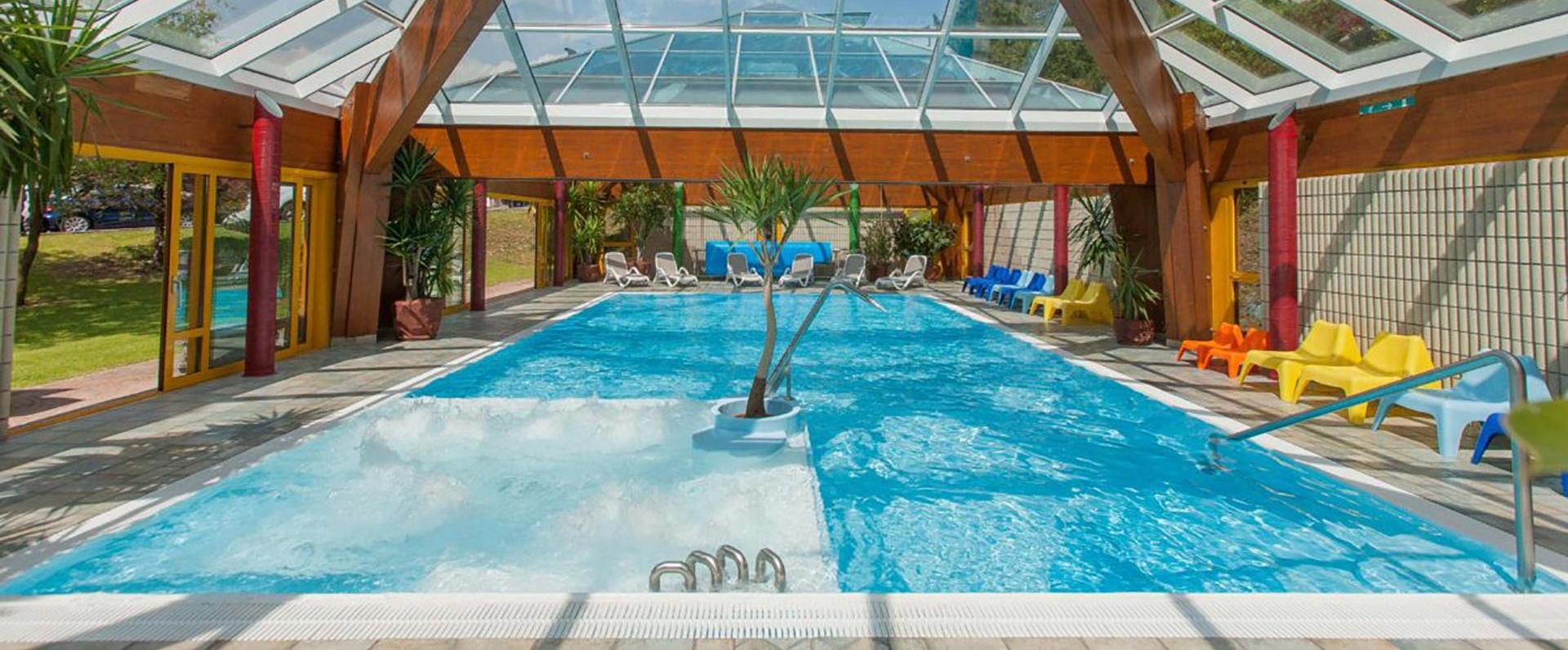 Bright indoor pool with colorful chairs, relaxing and welcoming atmosphere.