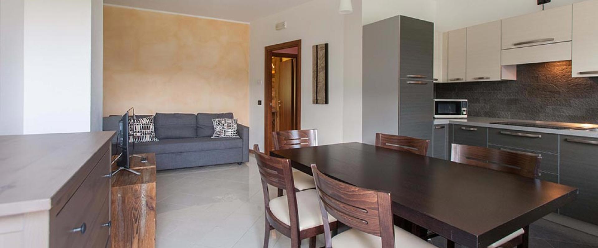 Modernes, gemütliches Wohnzimmer mit dunklem Tisch und eleganter Küche.