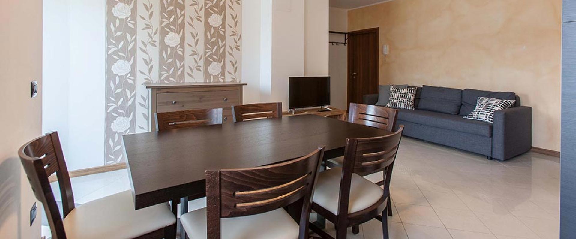 Modernes Wohnzimmer mit dunklem Tisch, grauem Sofa und dekorierten Wänden.
