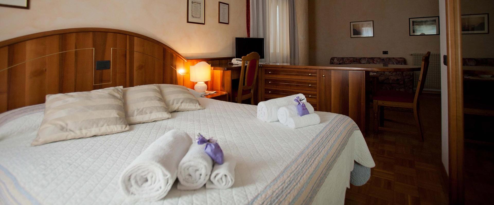Camera accogliente con letto matrimoniale, asciugamani e luce calda.