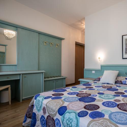 Cozy room with colorful bed and pastel green furniture, relaxing ambiance.